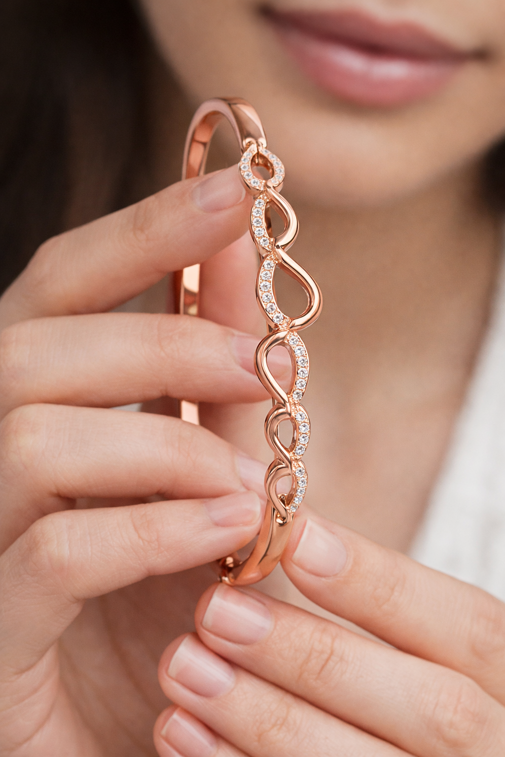 Rose gold bracelet with diamond accents held by a person