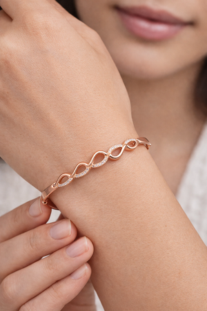 Rose gold plated sterling silver hinged bangle featuring a modern pave-set cubic zirconia wave design."